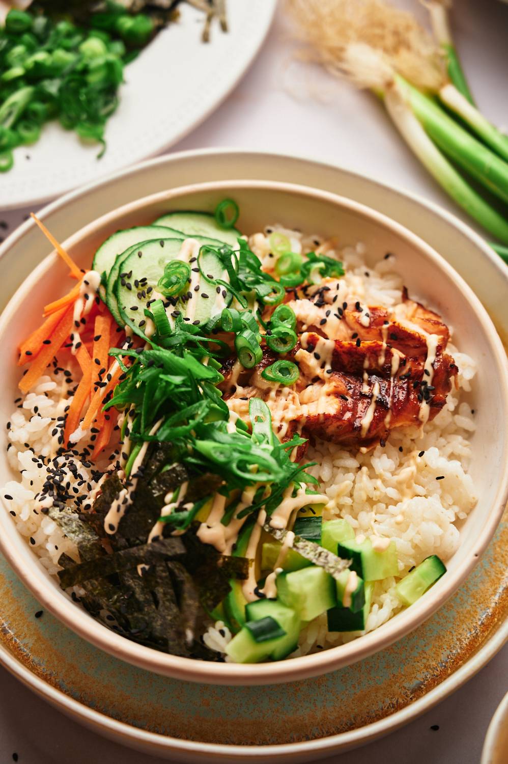 Sushi bowls with salmon, seaweed, spicy mayo, sushi rice, and vegetables.