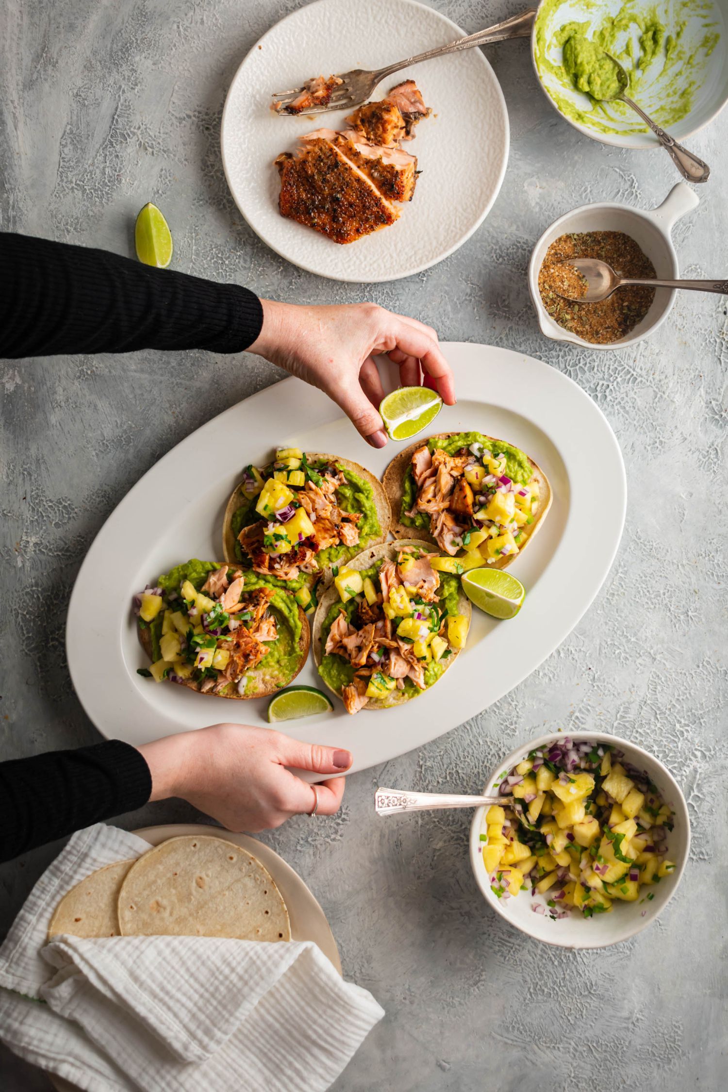 Plate with salmon tostadas served with baked salmon, pineapple salsa, avocado, and fresh cilantro.