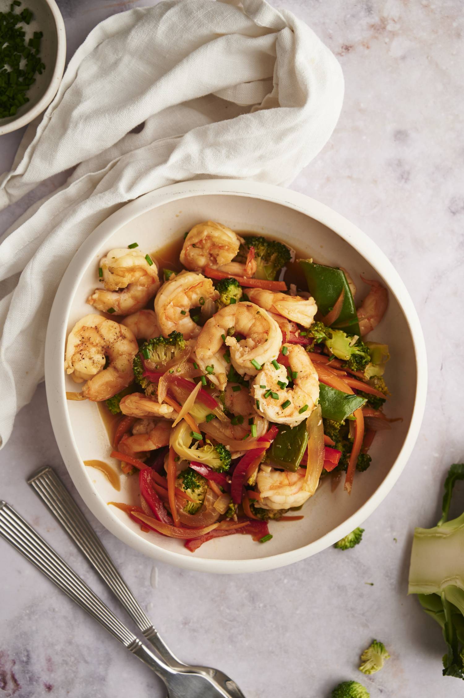 Vegetable and shrimp stir fry with broccoli, carrots, peppers, and snap peas in a bowl. 