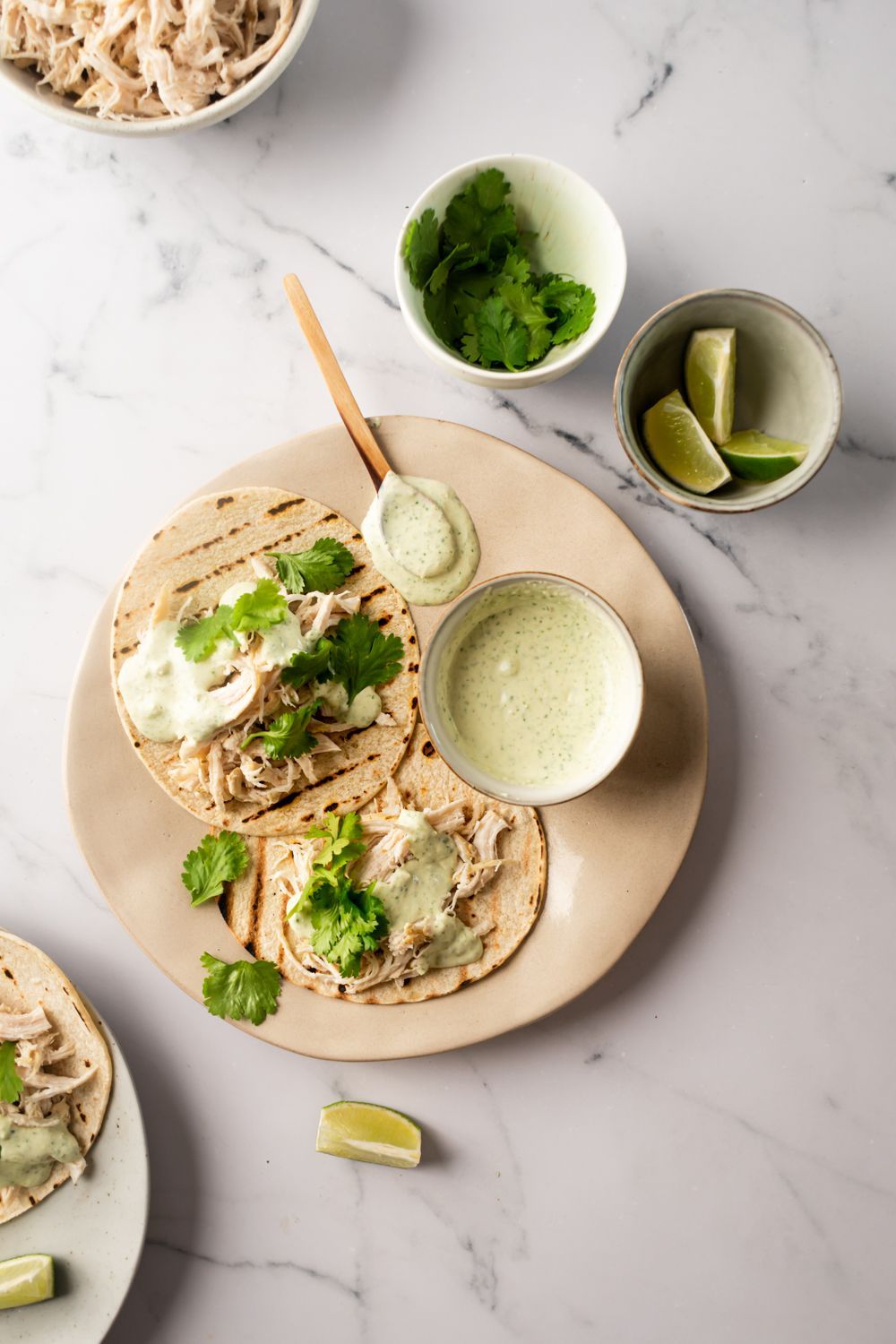 Chicken tacos with jalapenos and a creamy cilantro sauce made with yogurt and limes on a plate with corn tortillas