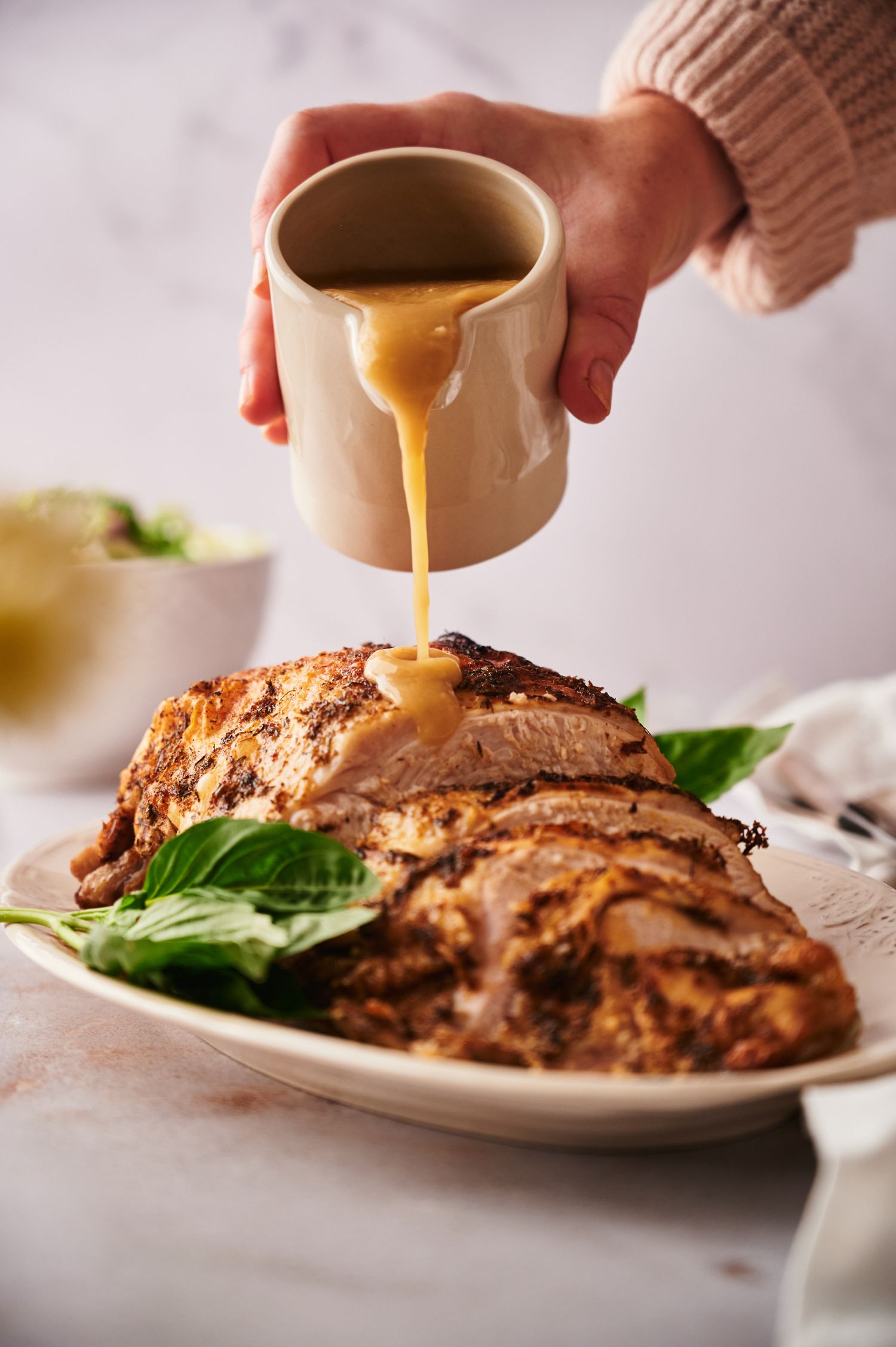 Gravy being poured on crockpot turkey breast served sliced on a plate.