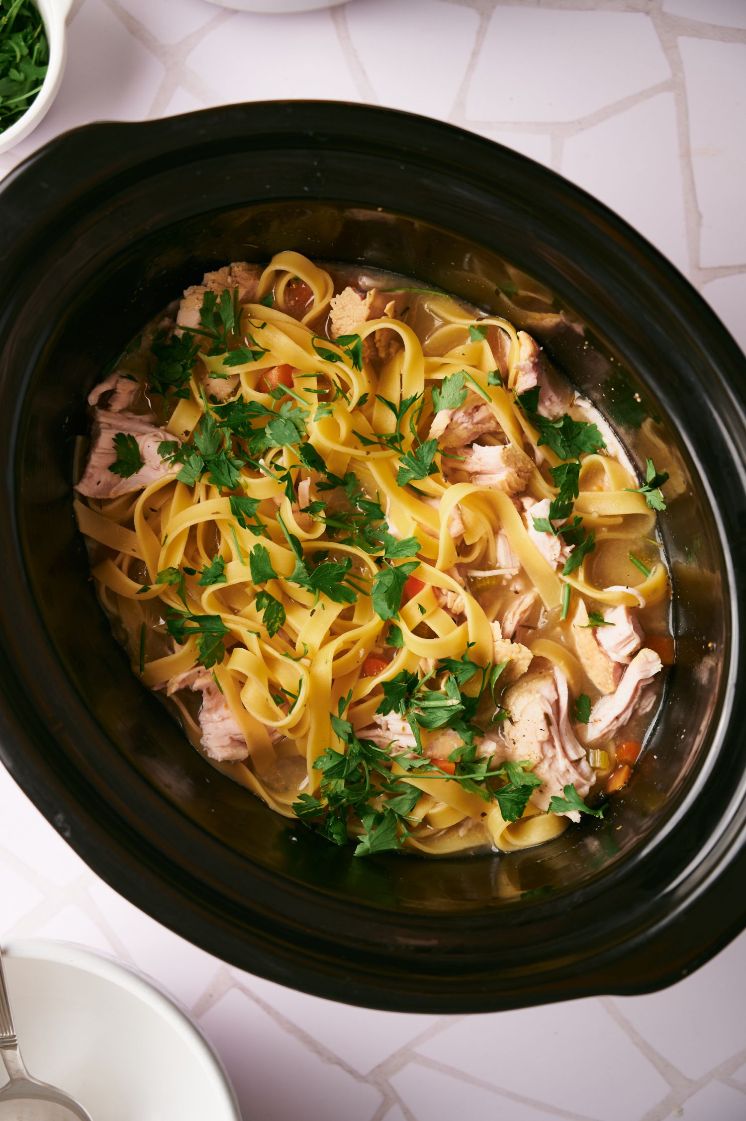 Turkey and noodle soup in a slow cooker with shredded turkey, vegetables, and noodles.