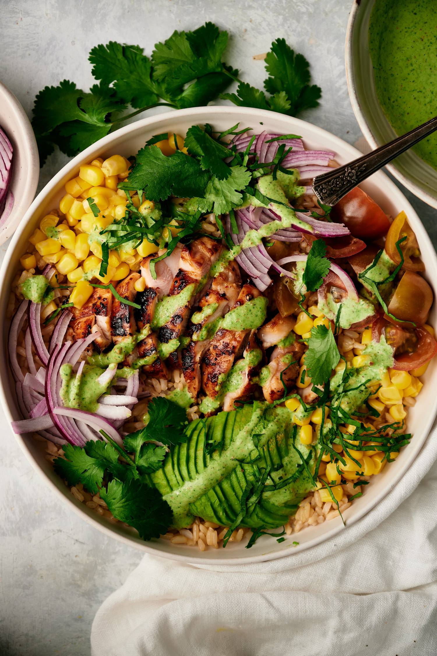 Chicken rice bowls with Southwestern flavors including spicy grilled chicken, corn, avocado, cilantro, and red onions.