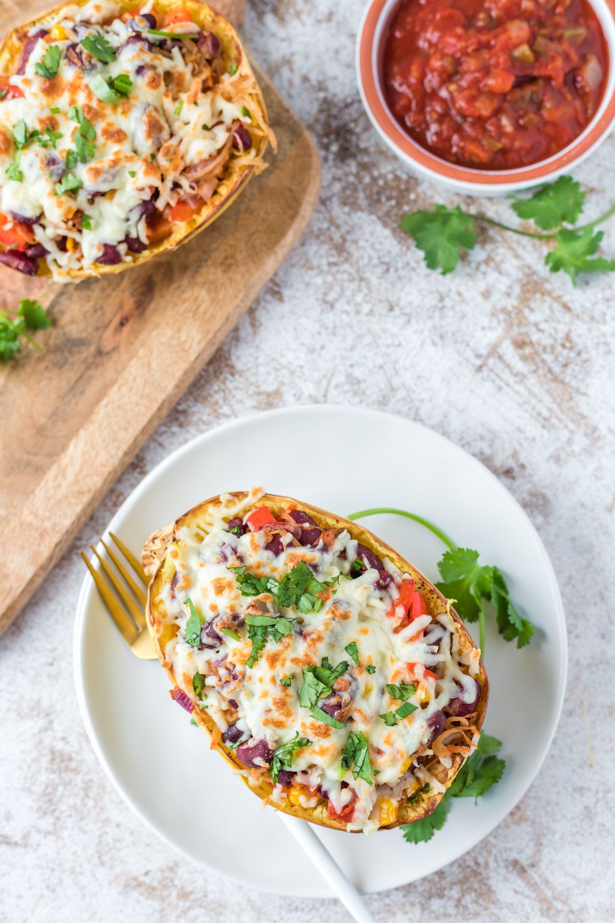 Stuffed spaghetti squash burritos with cilantro and salsa on the side.