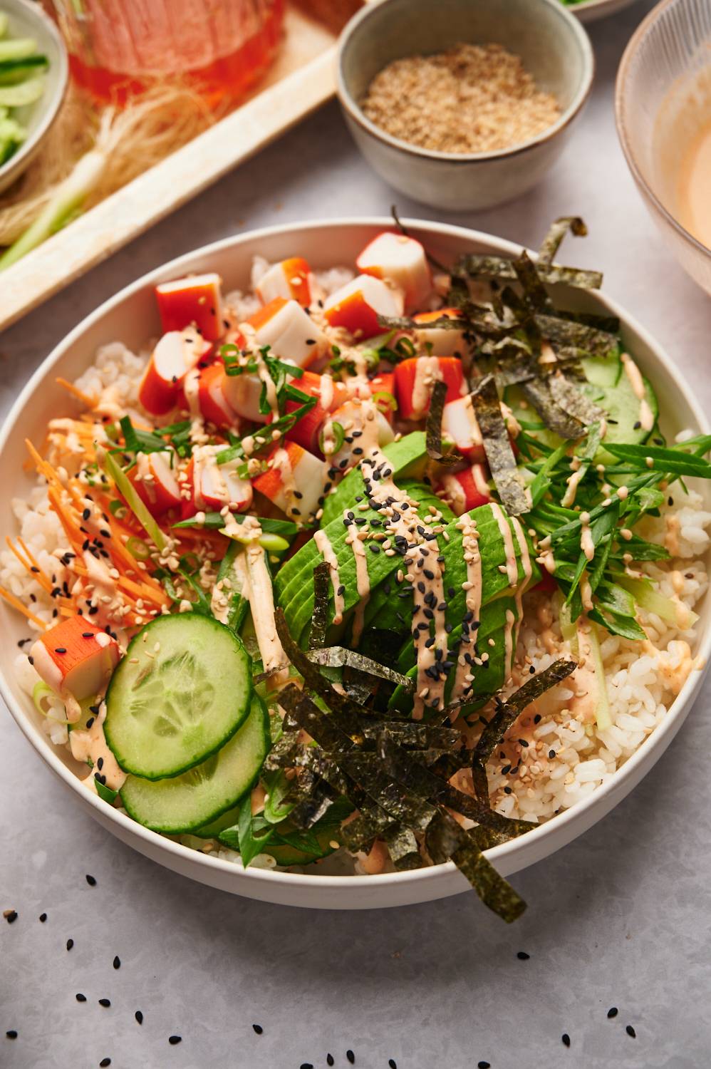 Sushi roll bowls with spicy mayo, crab, seaweed, rice, and vegetables. 