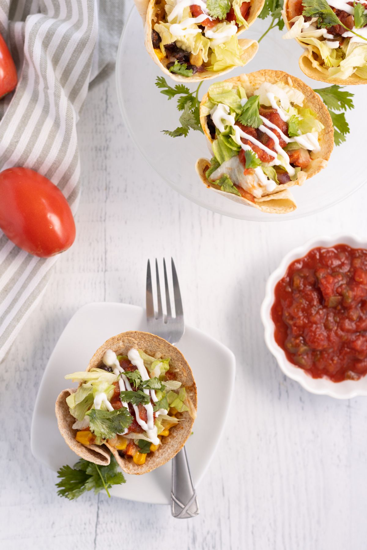 Baked taco cups with black beans, corn, salsa, and shredded cheese and topped with lettuce and salsa.