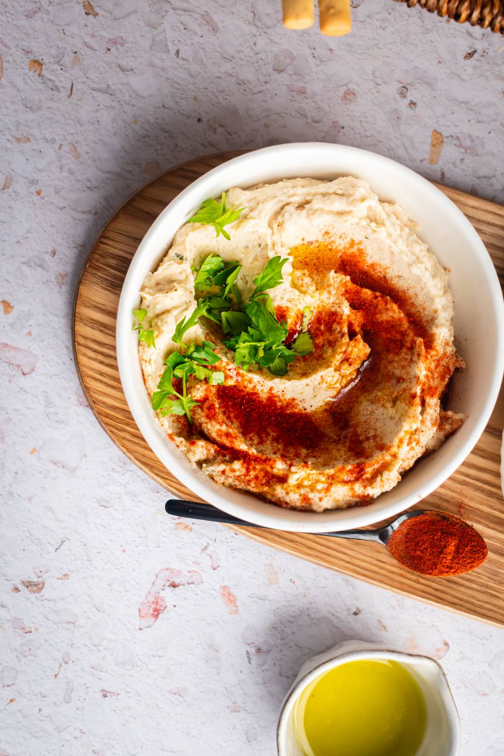 Creamy white bean hummus in a bowl with olive oil, herbs, and paprika.