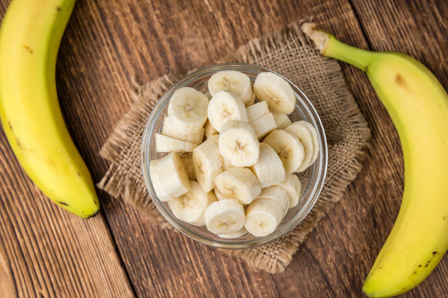 Bananas sliced and served in a bowl with fresh bananas on the side.