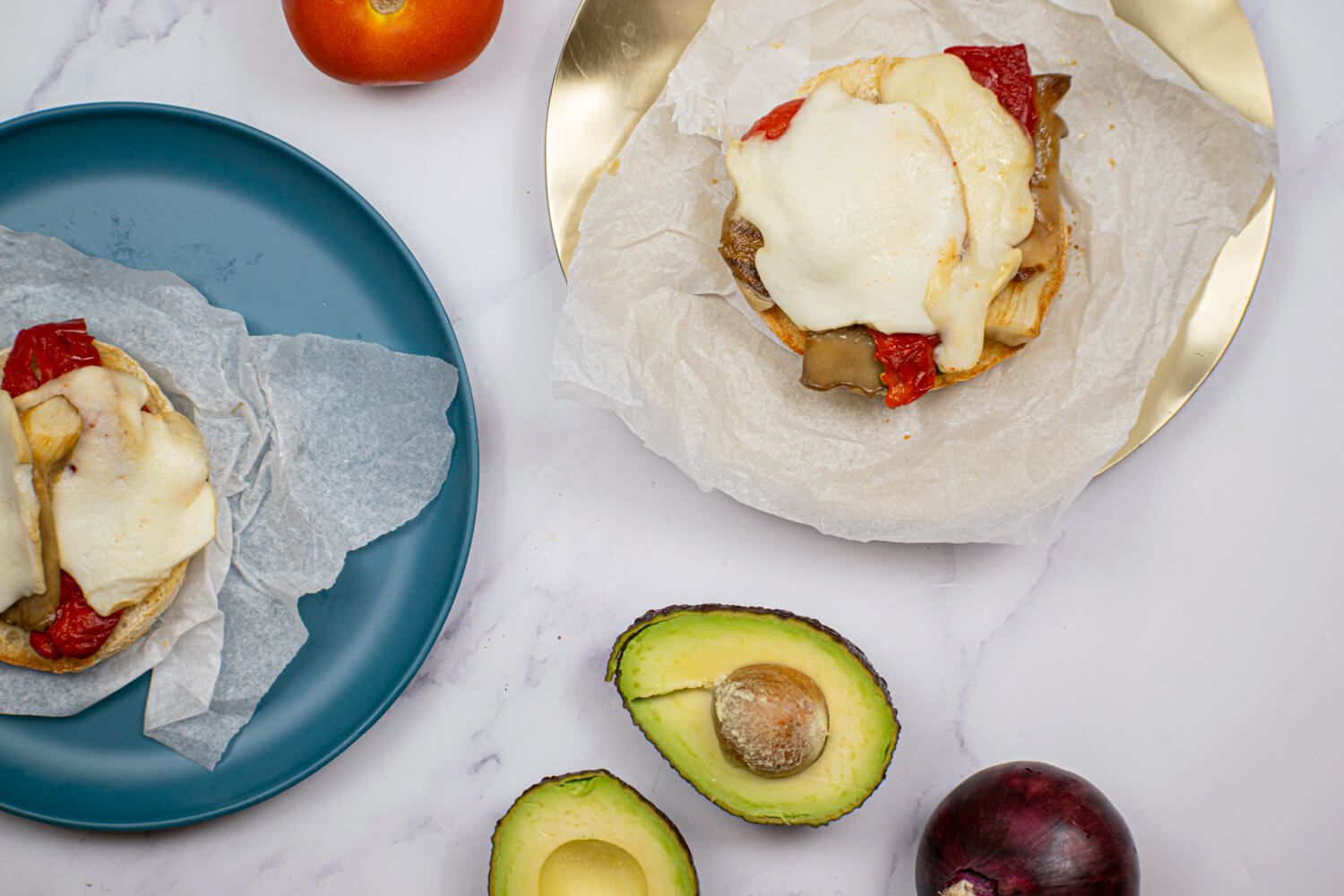 Portobello burger with red peppers, mozzarella, avocado, and red onion on a burger bun.