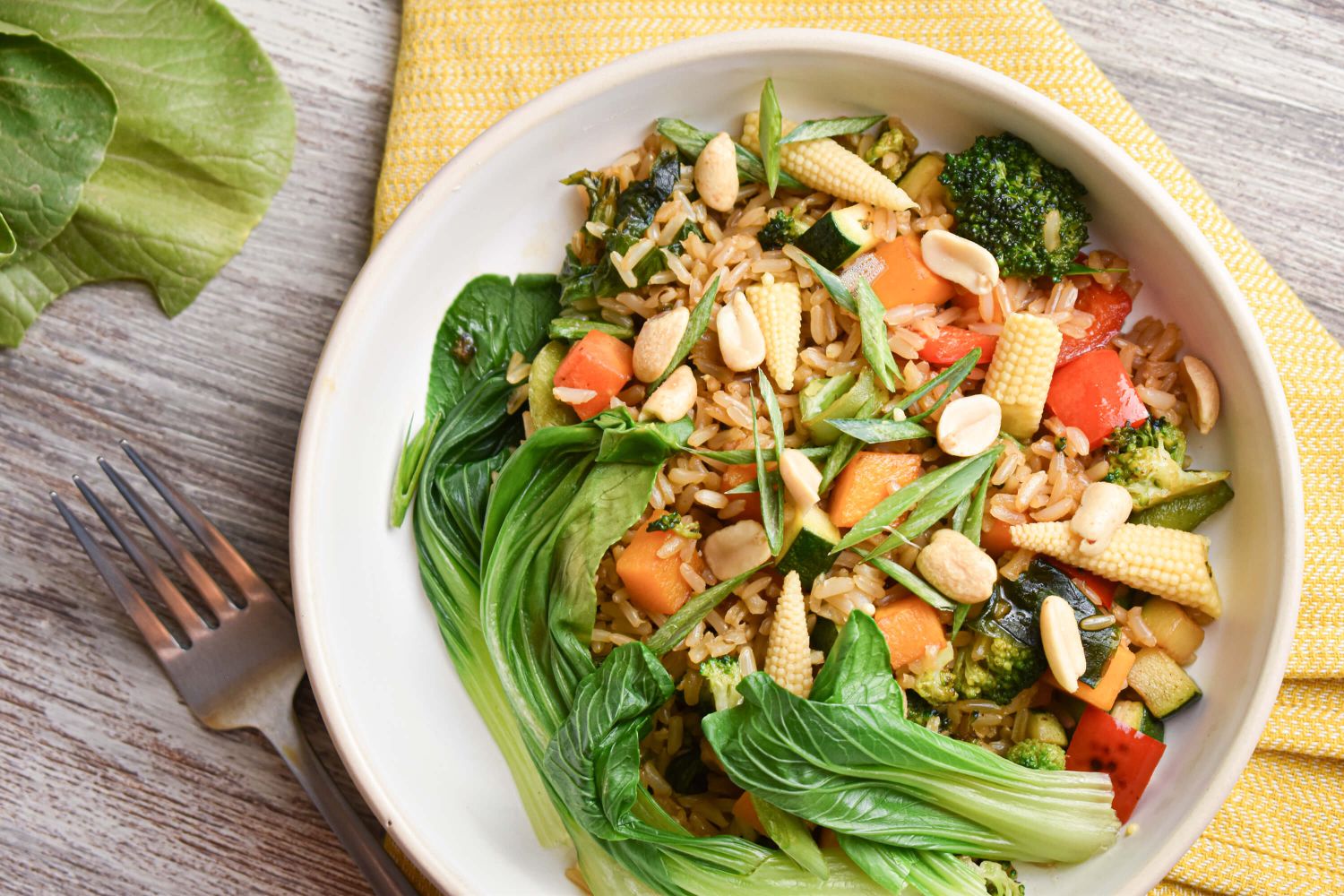 Teriyaki vegetable bowl with brown rice, bok choy, corn, edamame, carrots, and peanuts.