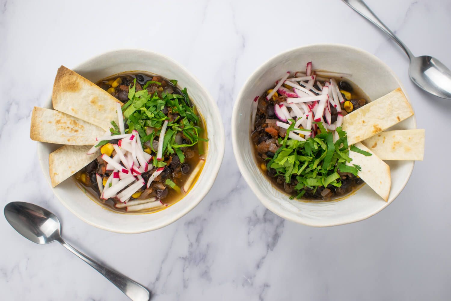 Vegetarian tortilla soup with radishes and cilantro on top with crispy tortilla strips.