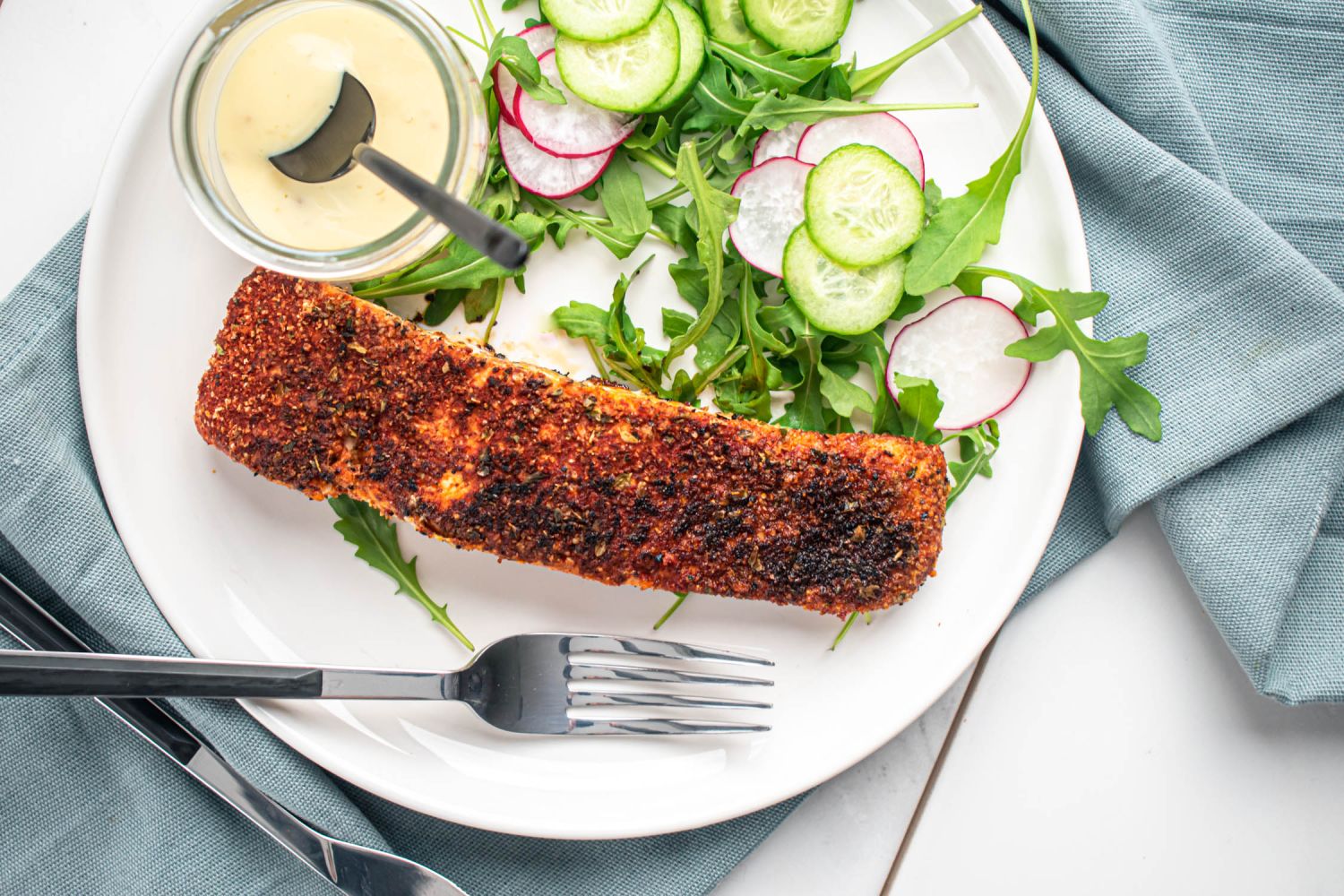 Blackened salmon with a homemade spice blend on a plate with salad.