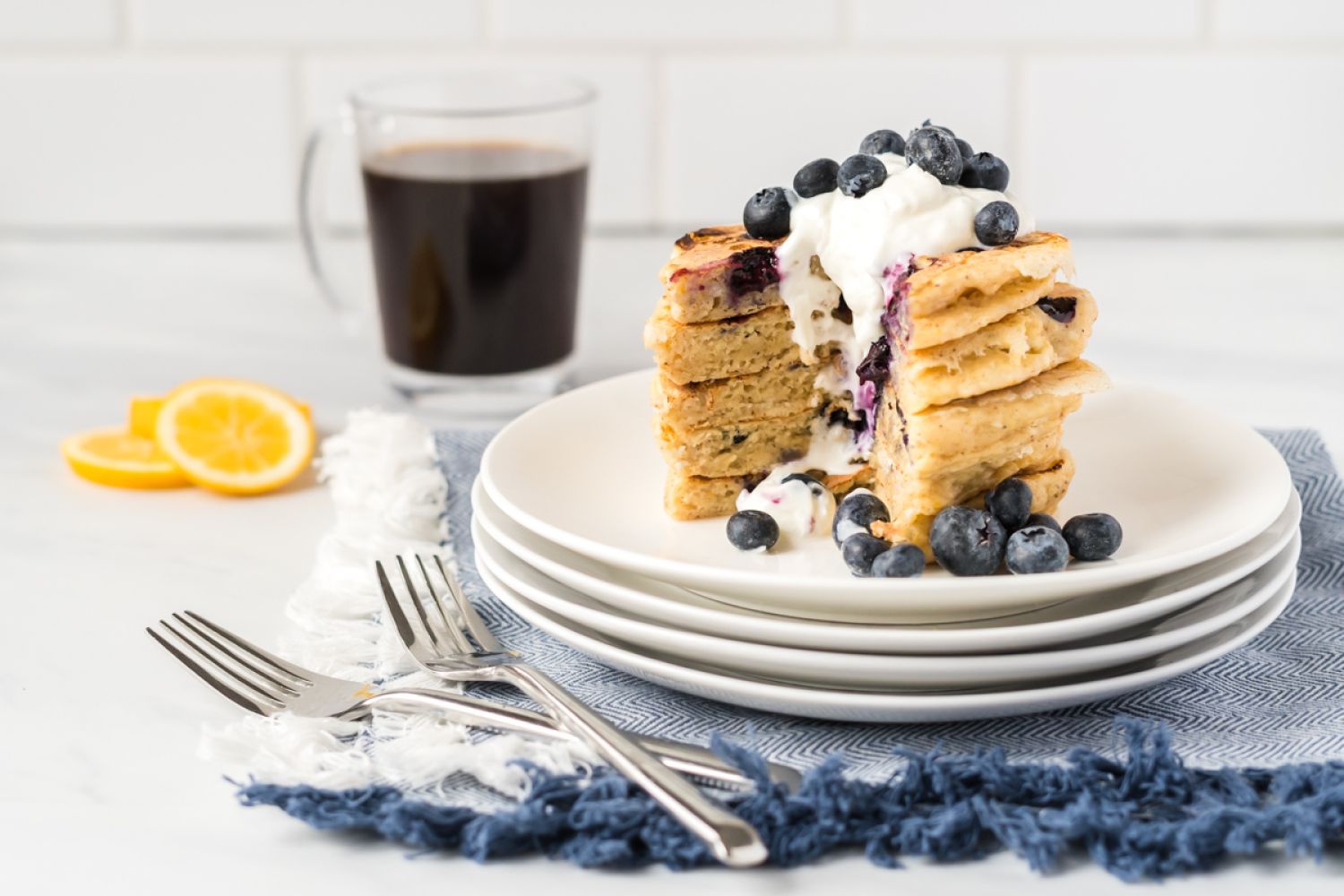 Blueberry lemon ricotta pancakes in a stack with with fresh blueberries and Greek yogurt.