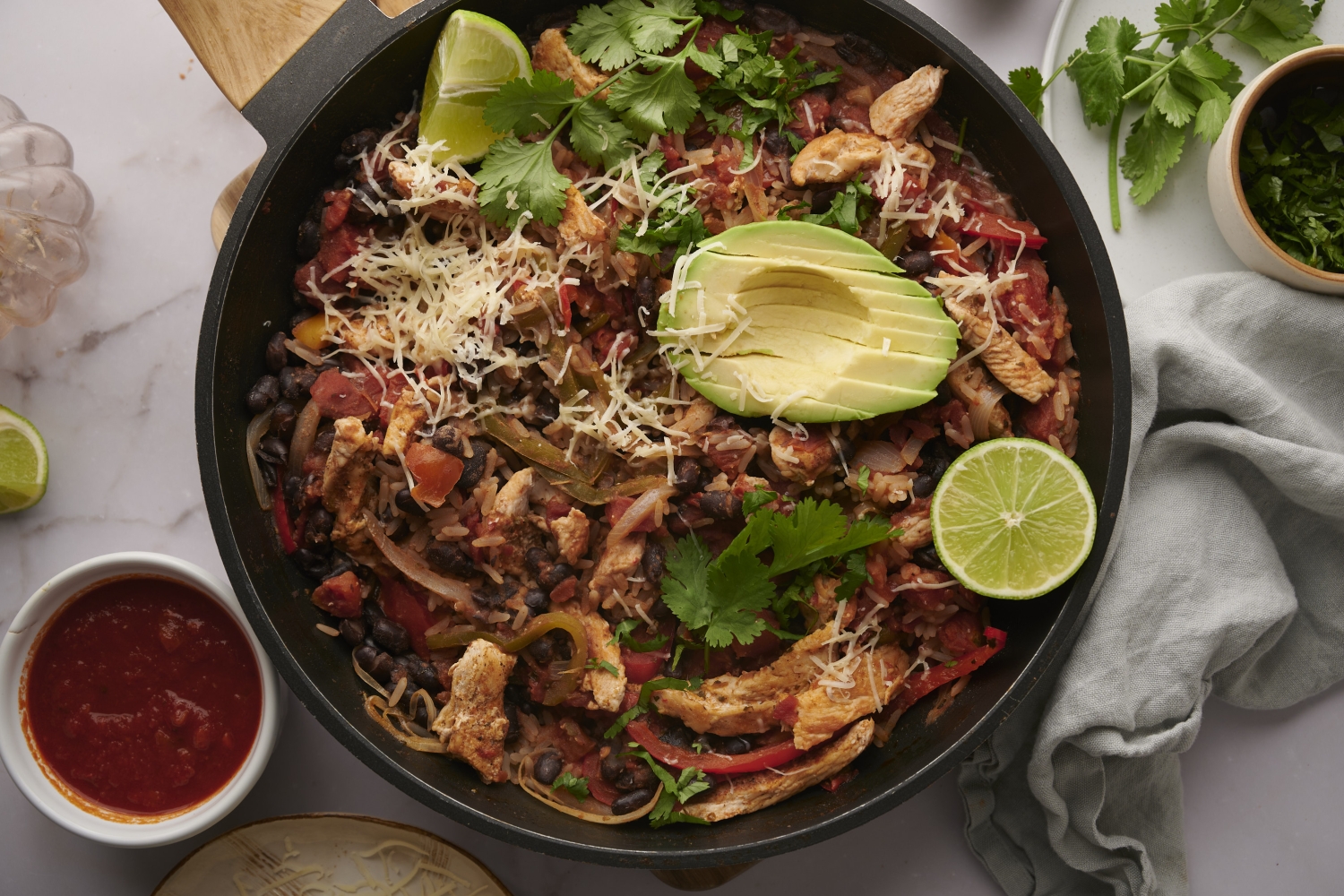 Chicken burrito bowls with chicken breast, peppers tomatoes, black bean, rice topped with avocado and cilantro.