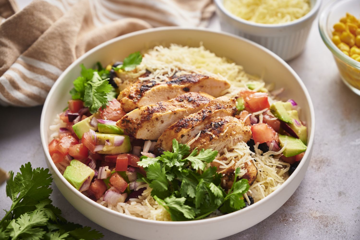 Chicken taco bowls with sliced grilled chicken, pico de gallo, avocado, cilantro, and rice.