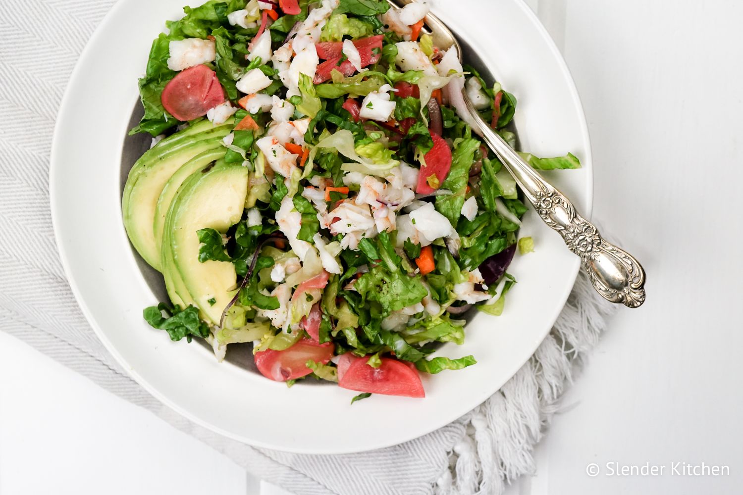 Chopped shrimp salad with fresh herbs, avocado, and a lemon vinaigrette in a bowll.