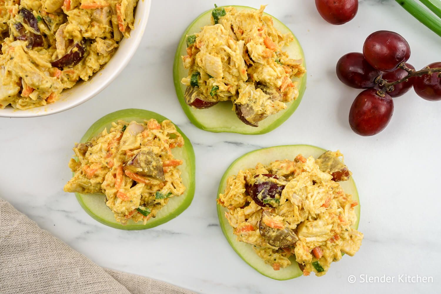 Curried chicken salad with grapes on apple slices.