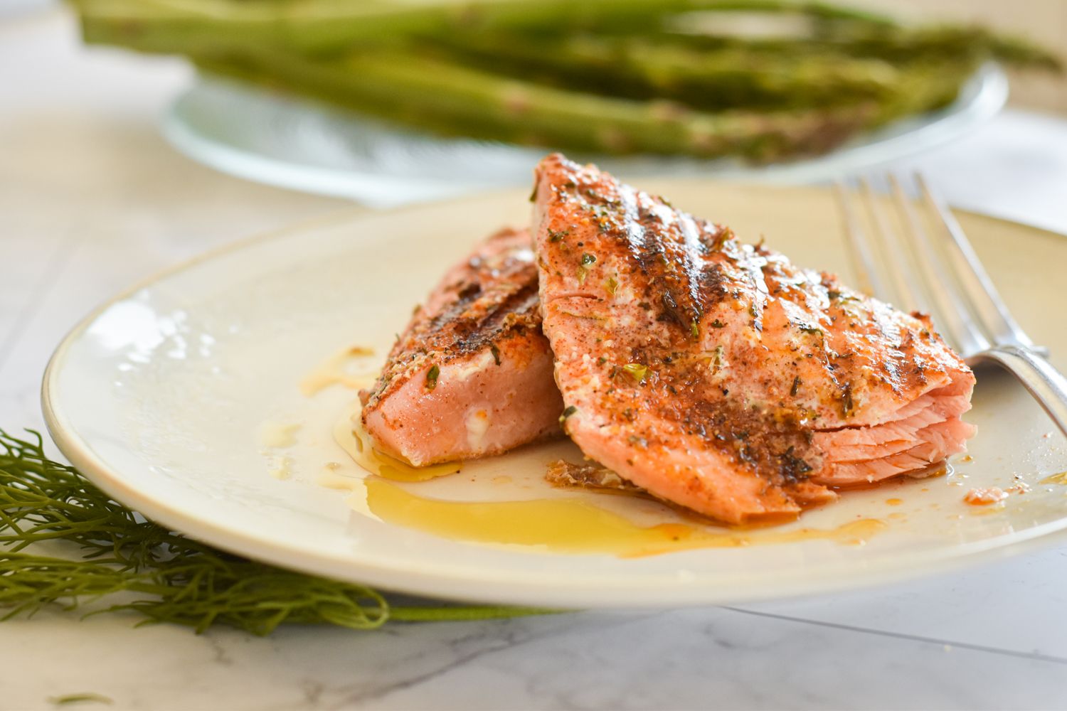 Grilled salmon with a Cajun spice rub on a plate with asparagus and salad./