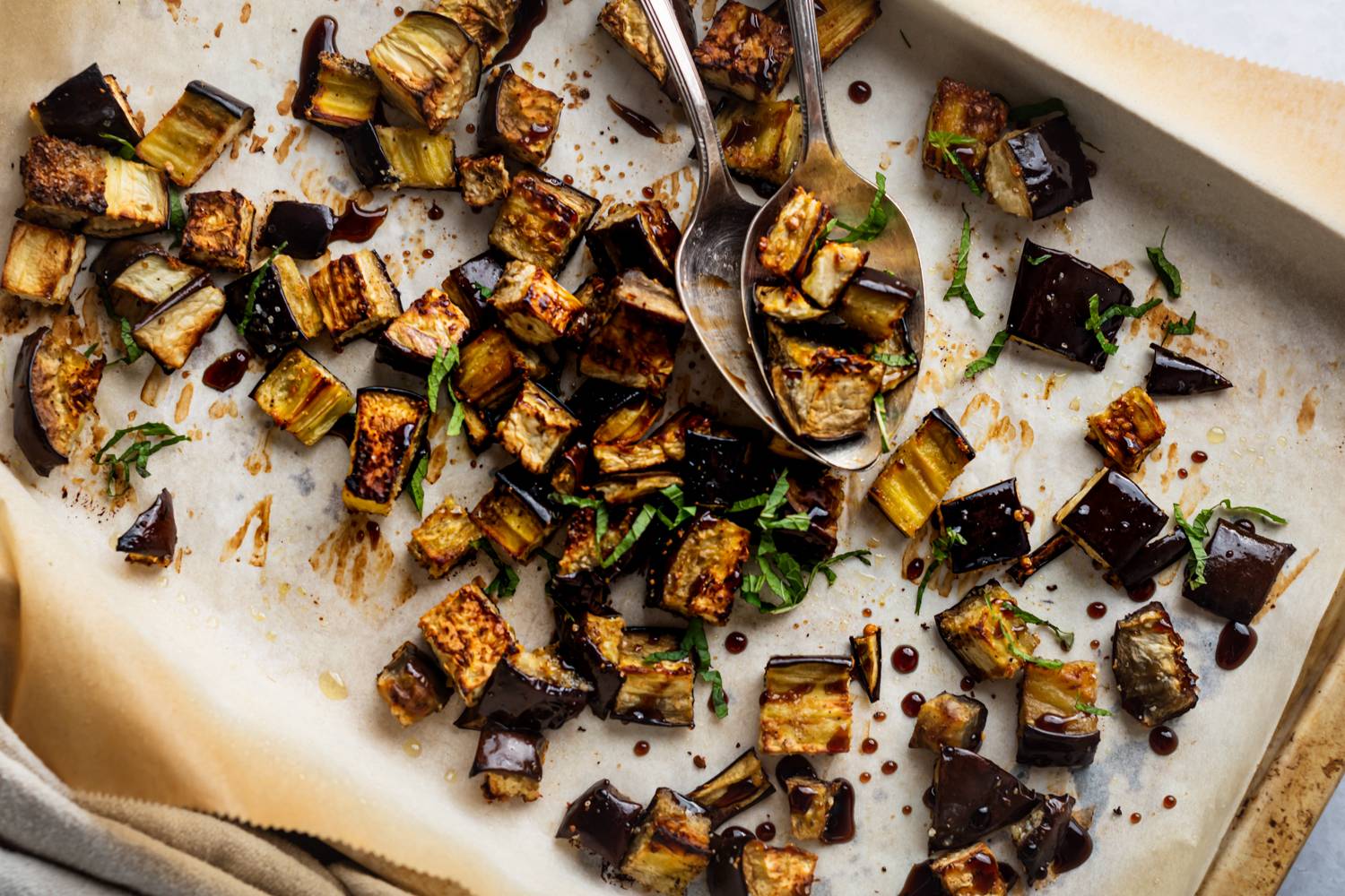 Garlic roasted eggplant on a baking sheet wtih balsamic vinegar, parsley, salt, and pepper.