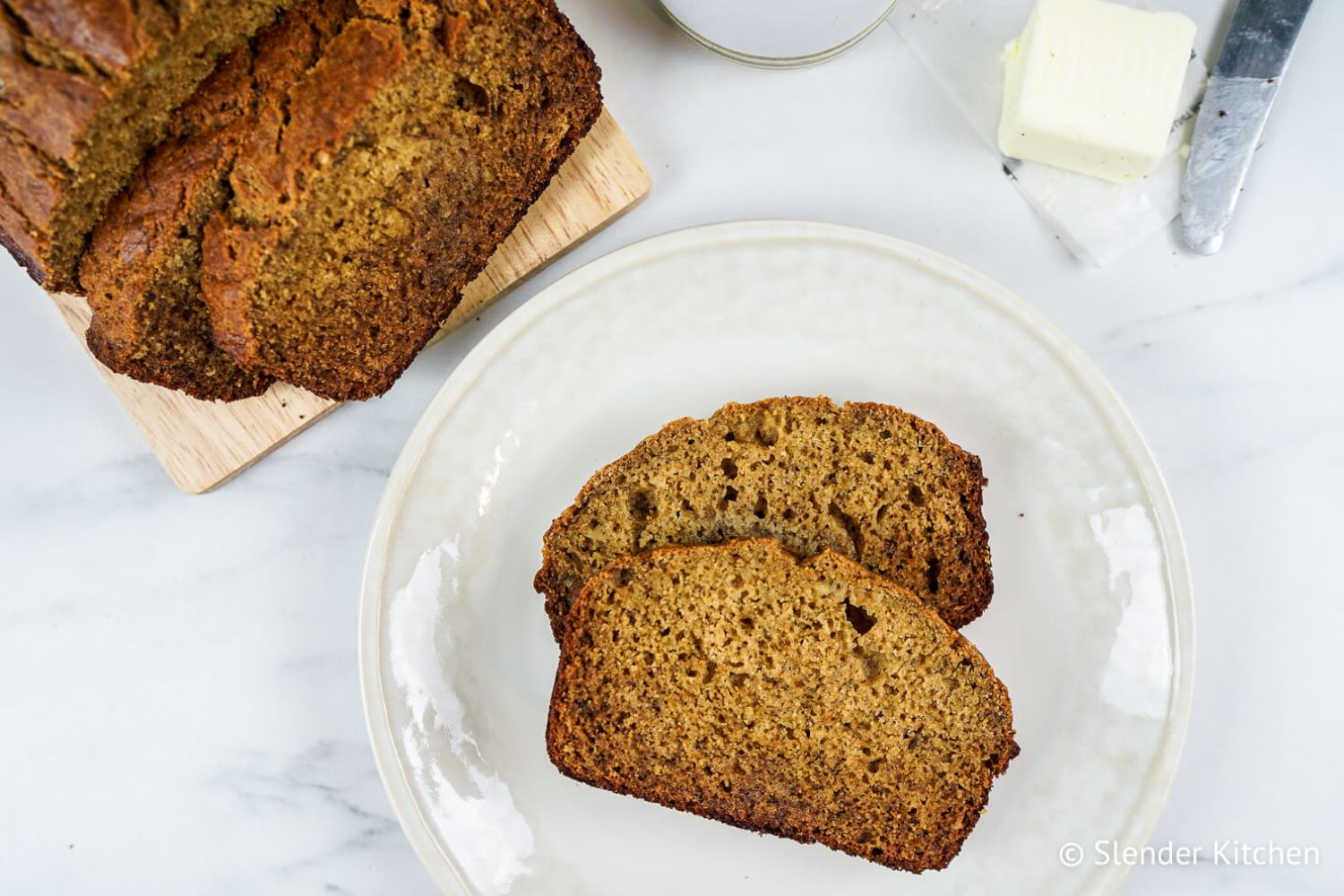 Healthy Cinnamon Banana Bread sliced on a plate with the whole loaf on the side.