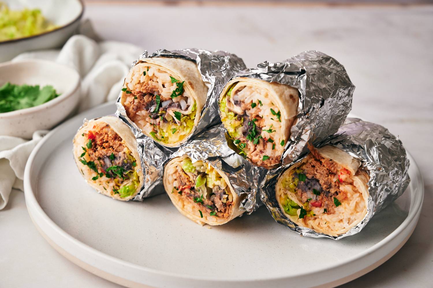 Machaca burritos with shredded beef, pinto beans, rice, cilantro, lettuce, cheese wrapped in flour tortillas and foil.