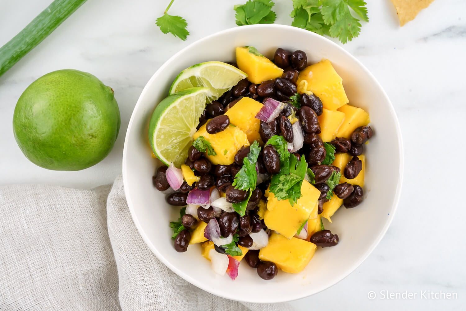 Mango salsa with fresh mango, black bans, red onion, cilantro, and lime juice in a bowl.