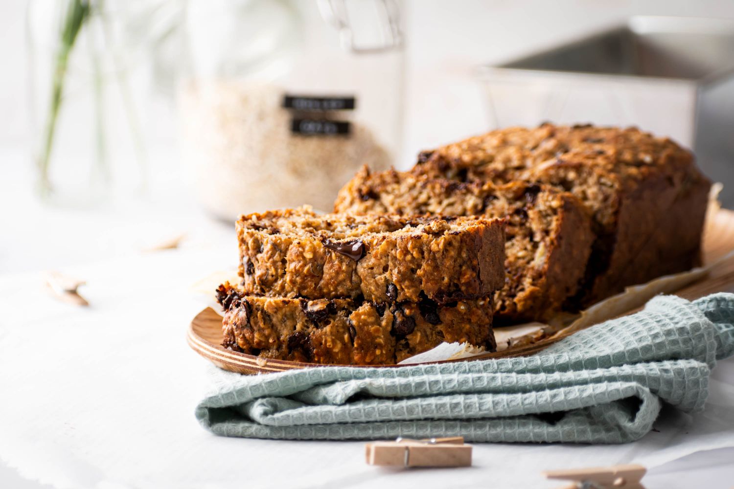 Oatmeal banana bread with chocolate chips sliced on a plate with a blue cloth napkin.