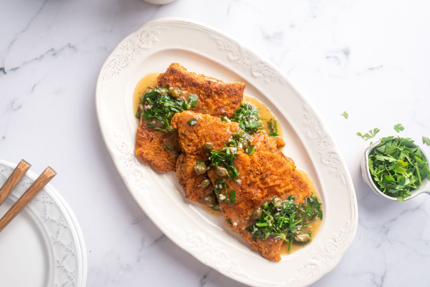 Pan seared cod with a crispy seasoned flour crust on a white plate with lemon garlic sauce.