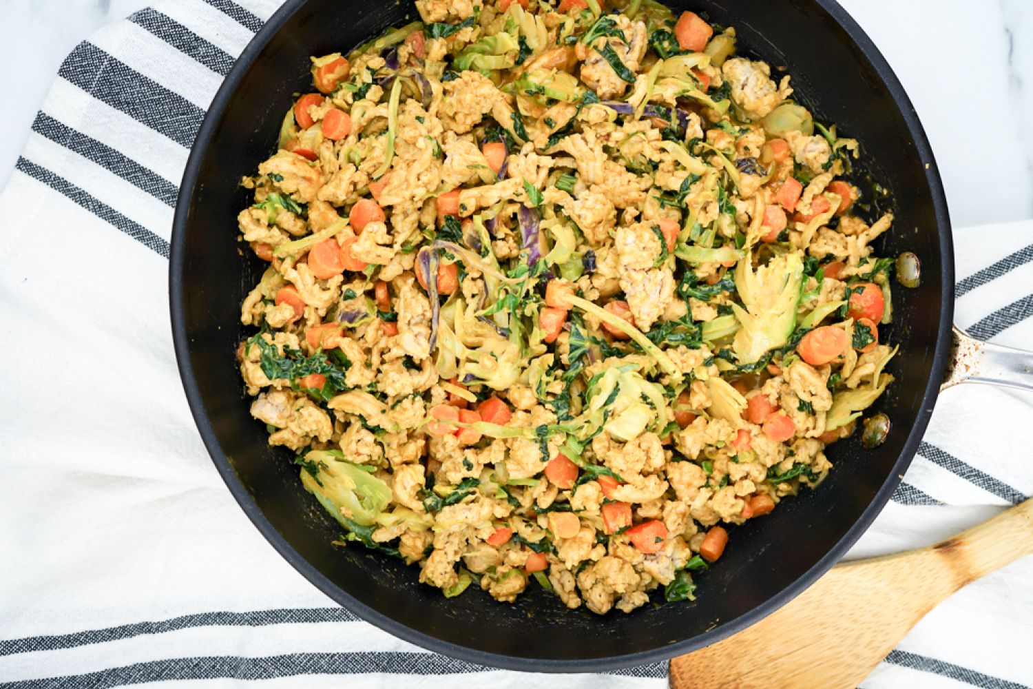 Peanut chicken stir-fry in a skillet with ground chicken, cabbage, carrots, and peanut sauce.