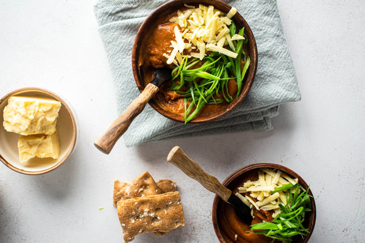 Quick an easy refried beans made with pinto beans in two bowls topped with green onions and cheese.