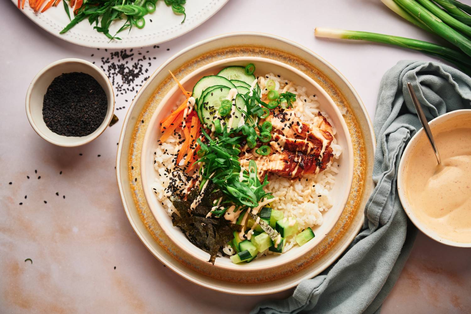 Salmon sushi bowls with sushi rice, salmon, seaweed strips, carrots, cucumbers, and spicy mayo. 