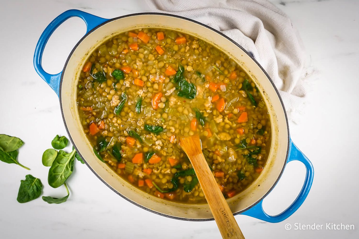 Sausage lentil soup with carrots, turkey sausage, celery, spinach, and brown lentils in a Dutch oven.