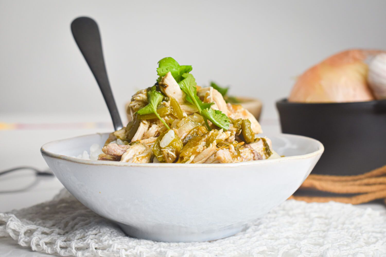 Slow cooker chicken chile verde with tomatillo salsa in a bowl with rice and cilantro.