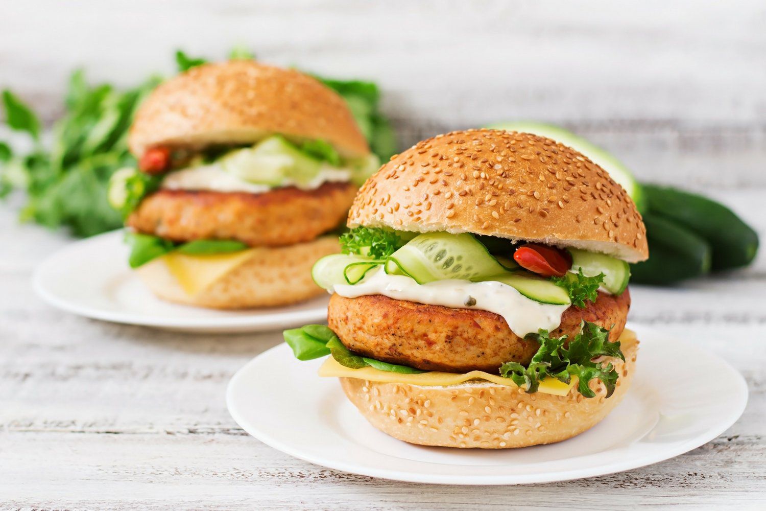 Fish burgers served on a hamburger bun with lettuce, tomato, and yogurt sauce.