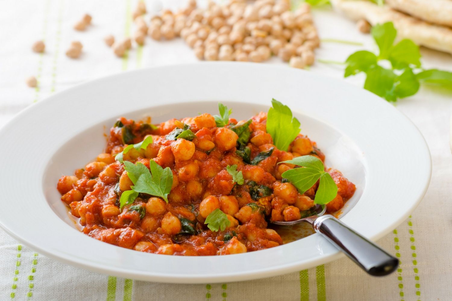 Tomato coconut curry chickpea stew with coconut milk, tomatoes, chickpeas, spinach, and potatoes in a bowl.