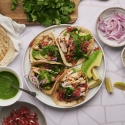 Mexican chicken tacos with tomatoes, onions, tortillas, salsa, and cilantro.