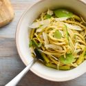 Creamy pesto pasta with zucchini, basil pesto, and Parmesan cheese in a ceramic bowl.