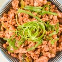 Healthy Mongolian chicken in a bowl with green onions on top.