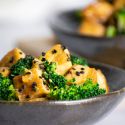 Sesame tofu with broccoli and sesame seeds in a small gray bowl.