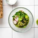 Aguachile with raw shrimp in a lime and cilantro sauce in a bowl with sliced cucumbers.