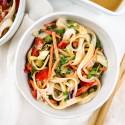 Asian noodle salad with almond dressing, rice noodles, and vegetables in a bowl with chopsticks.