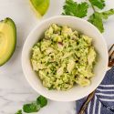 Avocado chicken salad with shredded chicken breast, avocados, lime juice, and cilantro in a bowl.