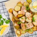 Baked fish and chips with crispy fish and potatoes on parchment paper with tarter sauce.