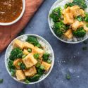 Baked tofu with sweet orange ginger sauce, broccoli, and rice in two bowls.