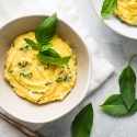 Basil Parmesan polenta in a bowl with fresh basil leaves on top.