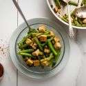 Basil tofu with green beans in a glass bowl with a skillet on the side.