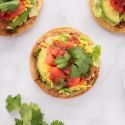 Tostadas with beans, cooked meat, shredded lettuce, tomatoes, avocado, and salsa.