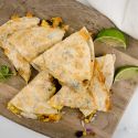 Breakfast quesadillas with eggs, corn, black beans, and cilantro on a cutting board.