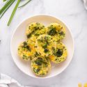 Broccoli Cheddar Egg Muffins with broccoli florets , green onions, and shredded cheese. 