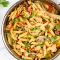 Chicken Fajita Pasta in a skillet with mushrooms, peppers, onions, and tomatoes.